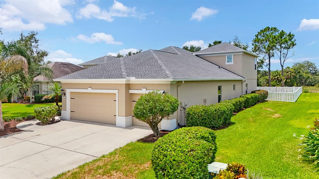 A beige house with a two-car garage and a gray shingled roof under a blue sky — 1416 HICKORY VIEW CIRCLE, PARRISH, FL