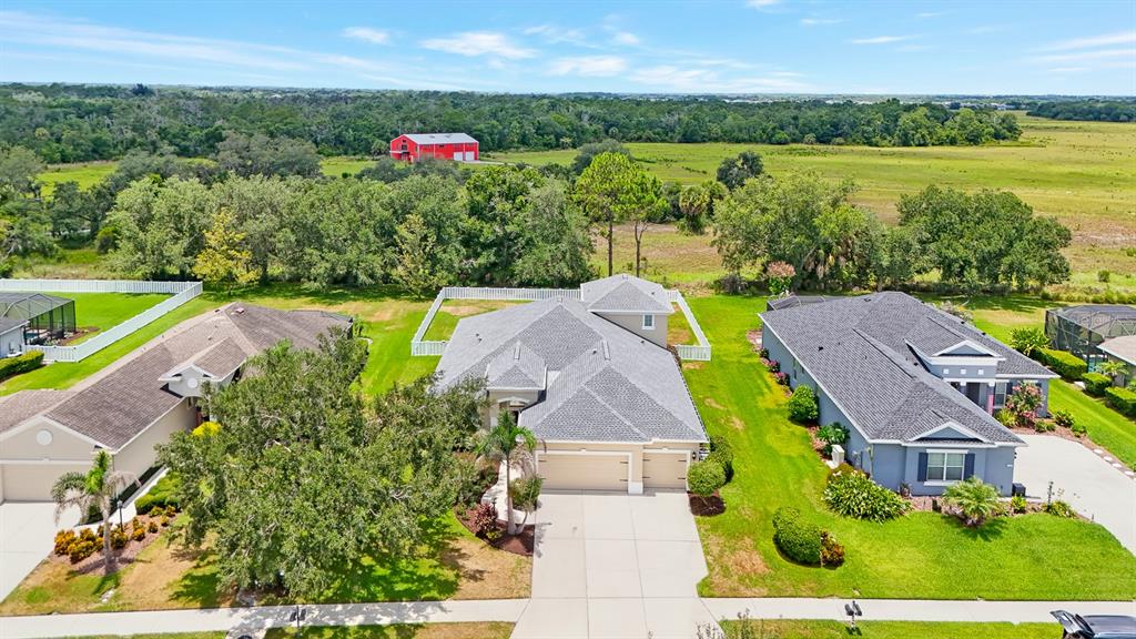 An aerial view shows three suburban houses with gray roofs and driveways near a field — 1416 HICKORY VIEW CIRCLE, PARRISH, FL
