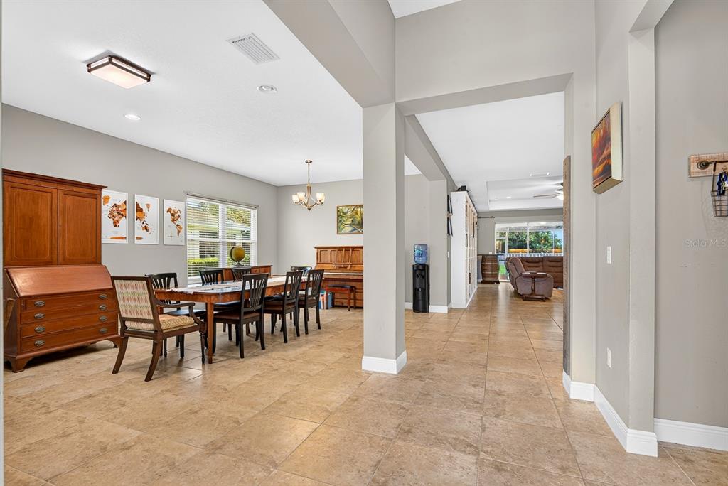 A dining room with a wooden table and piano leads into a tiled living area — 1416 HICKORY VIEW CIRCLE, PARRISH, FL