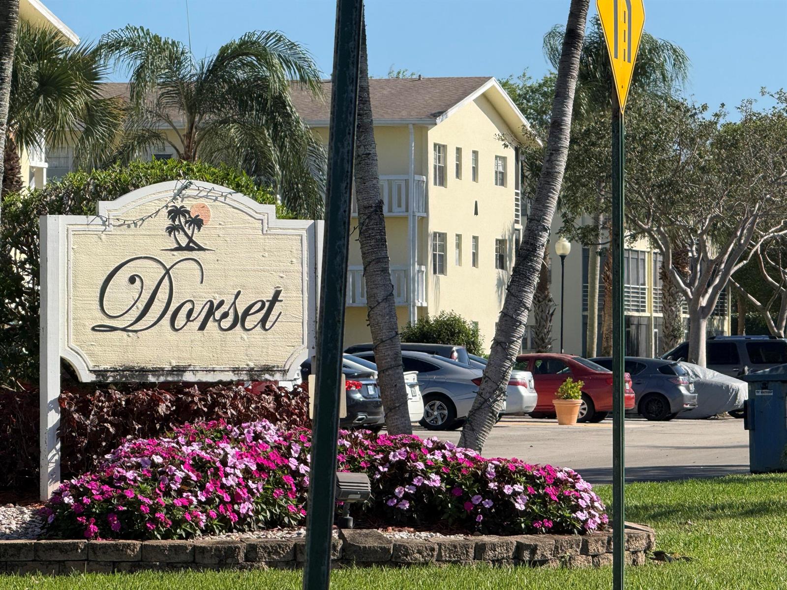 A sign for Dorset stands in front of a yellow apartment building and parked cars — 13 Dorset A, Boca Raton FL 33434, BOCA RATON, FL