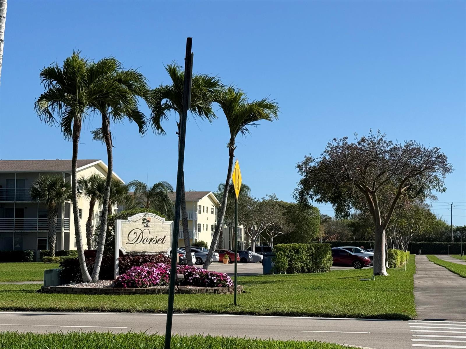 A sign for Dorset stands in front of palm trees, apartment buildings, and a parking lot — 13 Dorset A, Boca Raton FL 33434, BOCA RATON, FL
