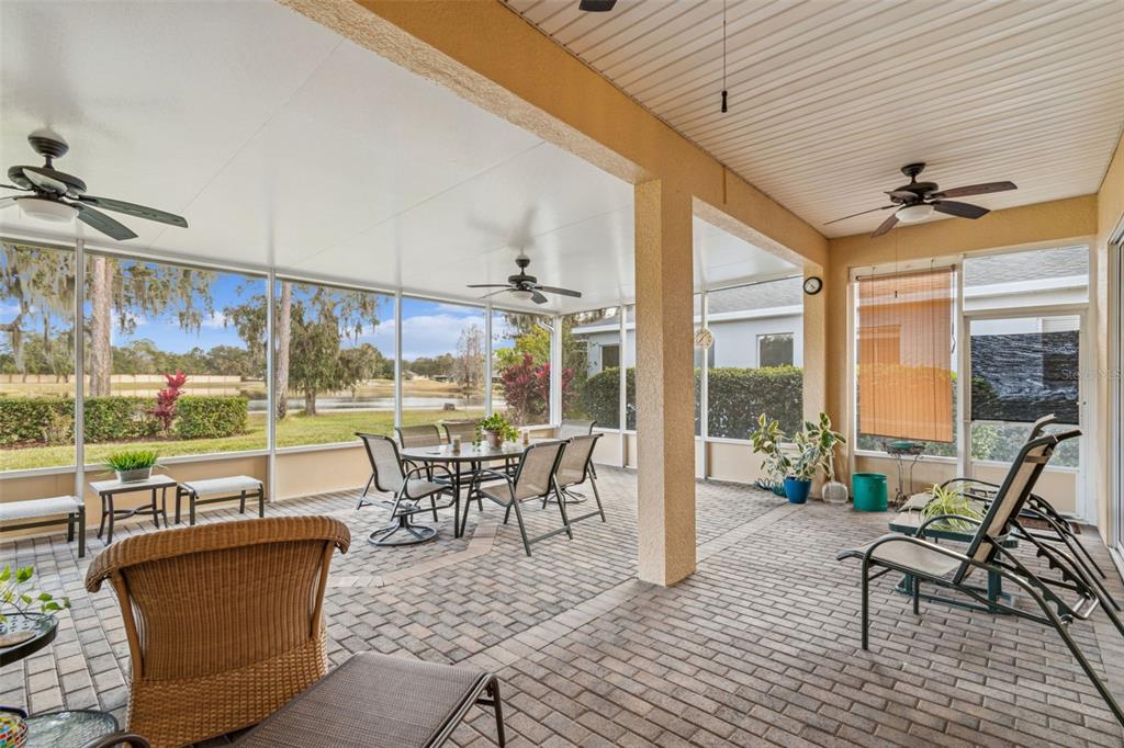 A screened-in patio features brick pavers, ceiling fans, and a view of a pond — 305 ROCK SPRINGS DRIVE, KISSIMMEE, FL