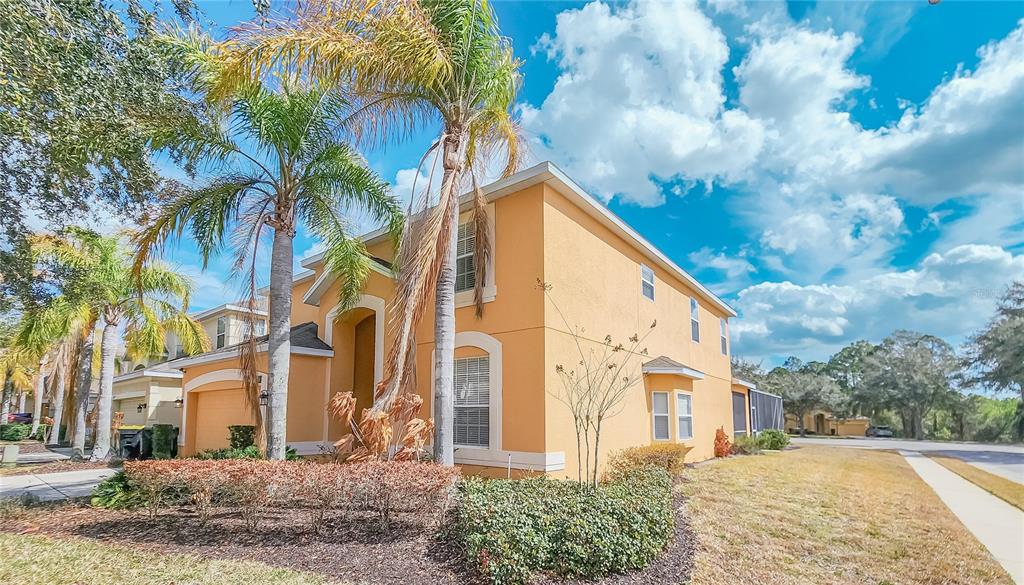 A two-story yellow stucco house with palm trees and a landscaped front yard — 1009 ORANGE COSMOS BOULEVARD, DAVENPORT, FL