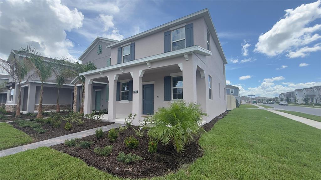 A two-story house with a covered front porch, gray shutters, and landscaped front yard — 1905 FULFILLMENT DRIVE, KISSIMMEE, FL