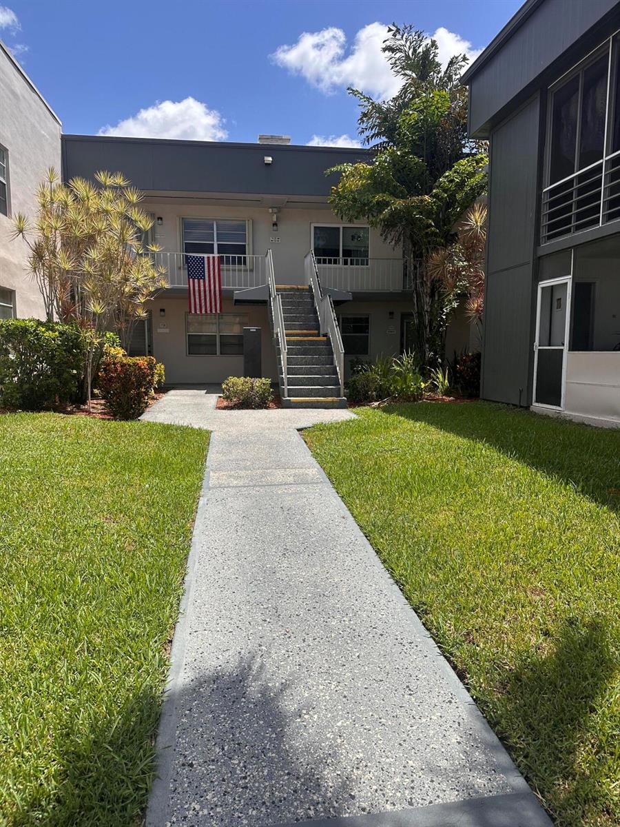 A concrete walkway leads to a two-story apartment building with an exterior staircase — 750 Burgundy P, Delray Beach FL 33484, DELRAY BEACH, FL