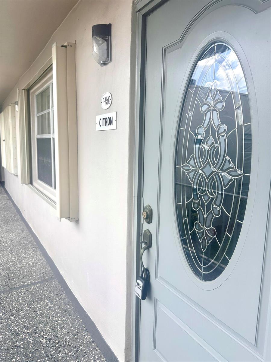 A light gray door with an oval glass insert features a lockbox on the handle — 750 Burgundy P, Delray Beach FL 33484, DELRAY BEACH, FL
