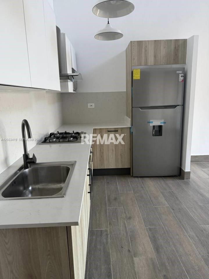 A modern kitchen features white upper cabinets, wood-grain lower cabinets, stainless steel appliances, and gray flooring — 1 1 # 1, FL, FL