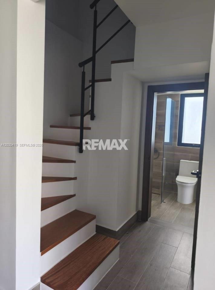 A wooden staircase with a black metal railing sits next to a bathroom doorway — 1 1 # 1, FL, FL
