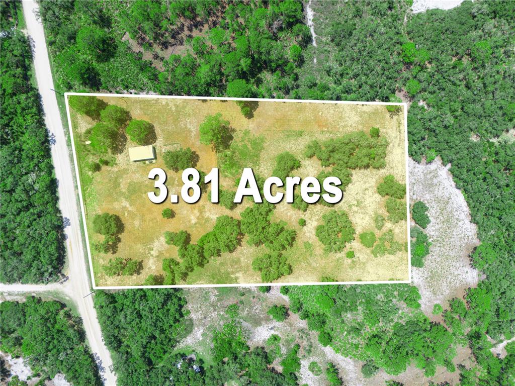 An aerial view shows a 3.81-acre rectangular plot of land featuring trees and a small structure — 1202 R E BYRD RD, FROSTPROOF, FL