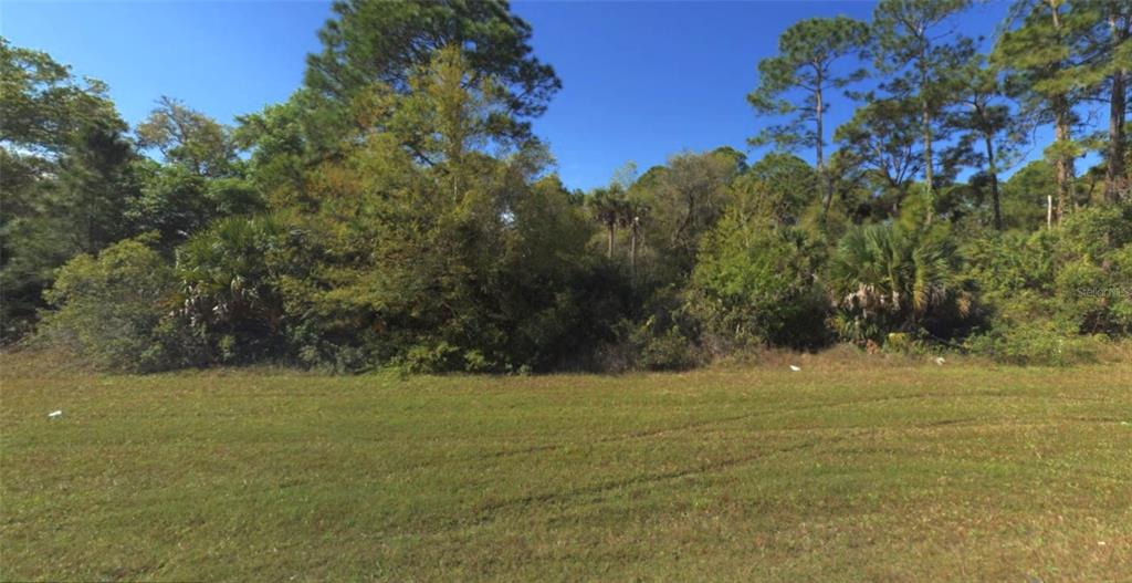 A grassy, open lot is bordered by a dense line of trees and shrubs — 1573, 1565 & 1557 BISCAYNE DRIVE, PORT CHARLOTTE, FL