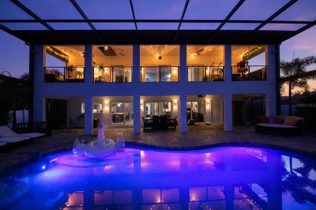 A screened-in pool patio overlooks a grassy backyard, palm trees, and a waterfront dock — 2424 HARBOUR DRIVE, PUNTA GORDA, FL
