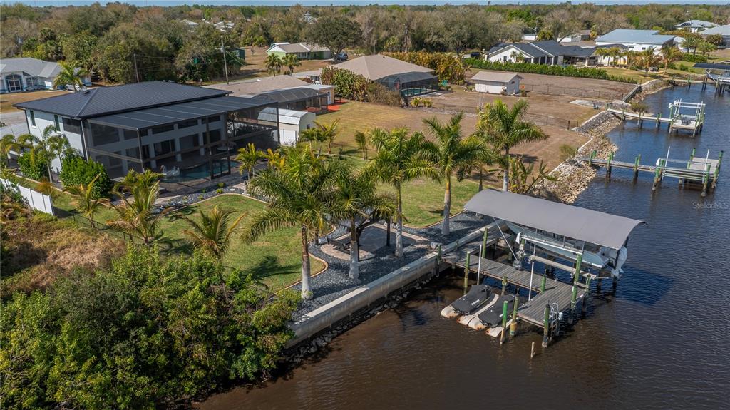 A backyard features a screened-in house, a covered gazebo, a flagpole, and palm trees — 2424 HARBOUR DRIVE, PUNTA GORDA, FL