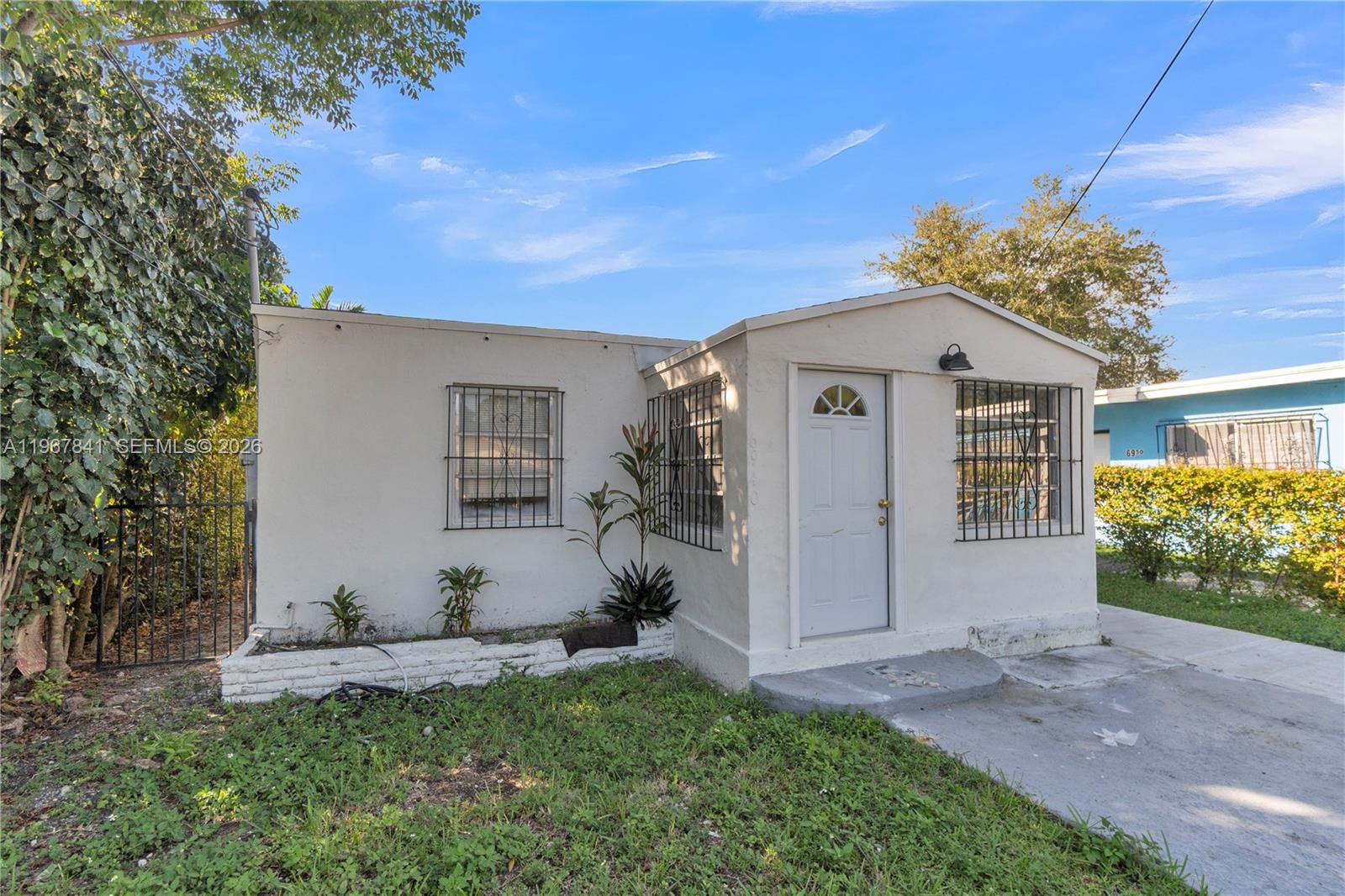 A small, white, single-story house with barred windows and a front entrance door — 6940 NW 6th Ct # 2, Miami FL 33150, MIAMI, FL