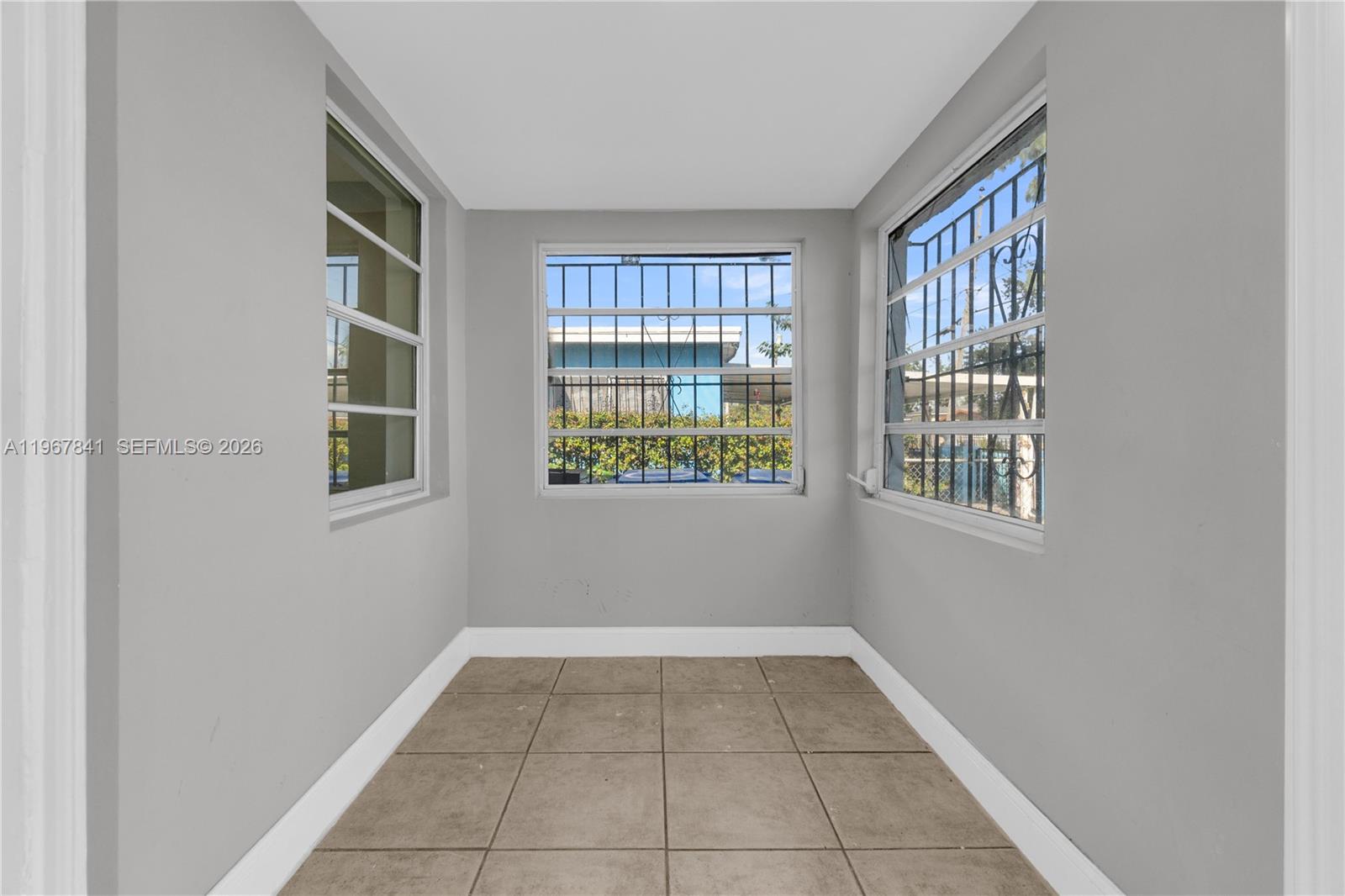 A small, gray-walled room features tiled flooring and three windows with security bars — 6940 NW 6th Ct # 2, Miami FL 33150, MIAMI, FL