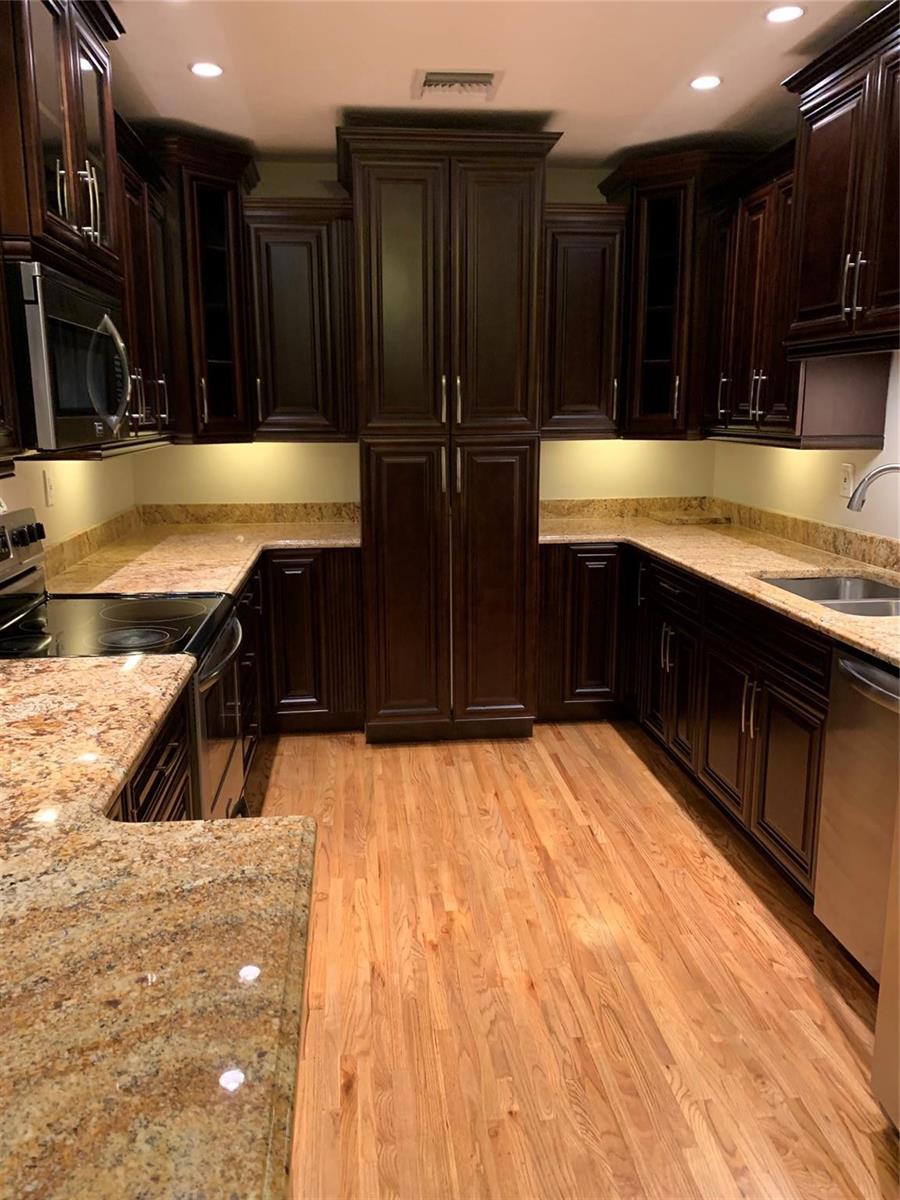 A kitchen features dark wood cabinetry, granite countertops, stainless steel appliances, and hardwood flooring — 2910 SW 103rd Place, Miami FL 33165, MIAMI, FL