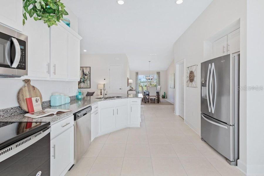 A kitchen with white cabinets, stainless steel appliances, and granite countertops opens to a dining area — 9393 HIGHLAND HILLS DR STREET, HUDSON, FL