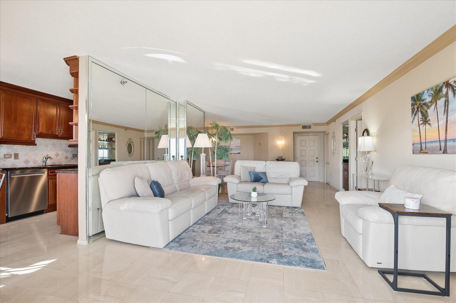 A living room with white leather sofas, a blue area rug, and mirrored wall panels — 1201 S Ocean # 704s, Hollywood FL 33019, HOLLYWOOD, FL