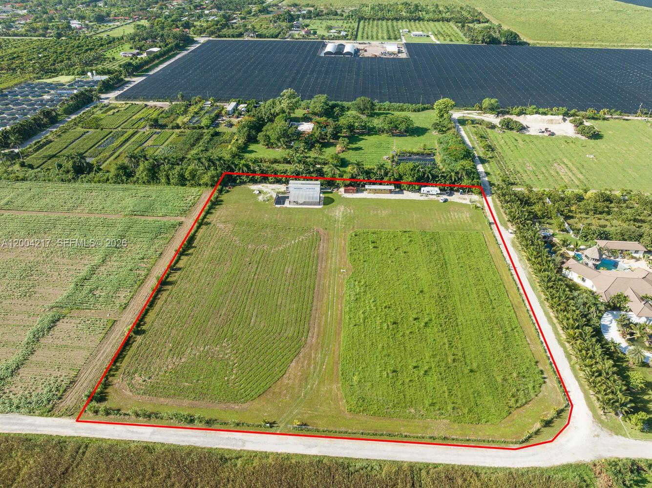 An aerial view shows a rectangular plot of land with a building and open fields — 21750 SW 226 terrace, FL 33170, FL