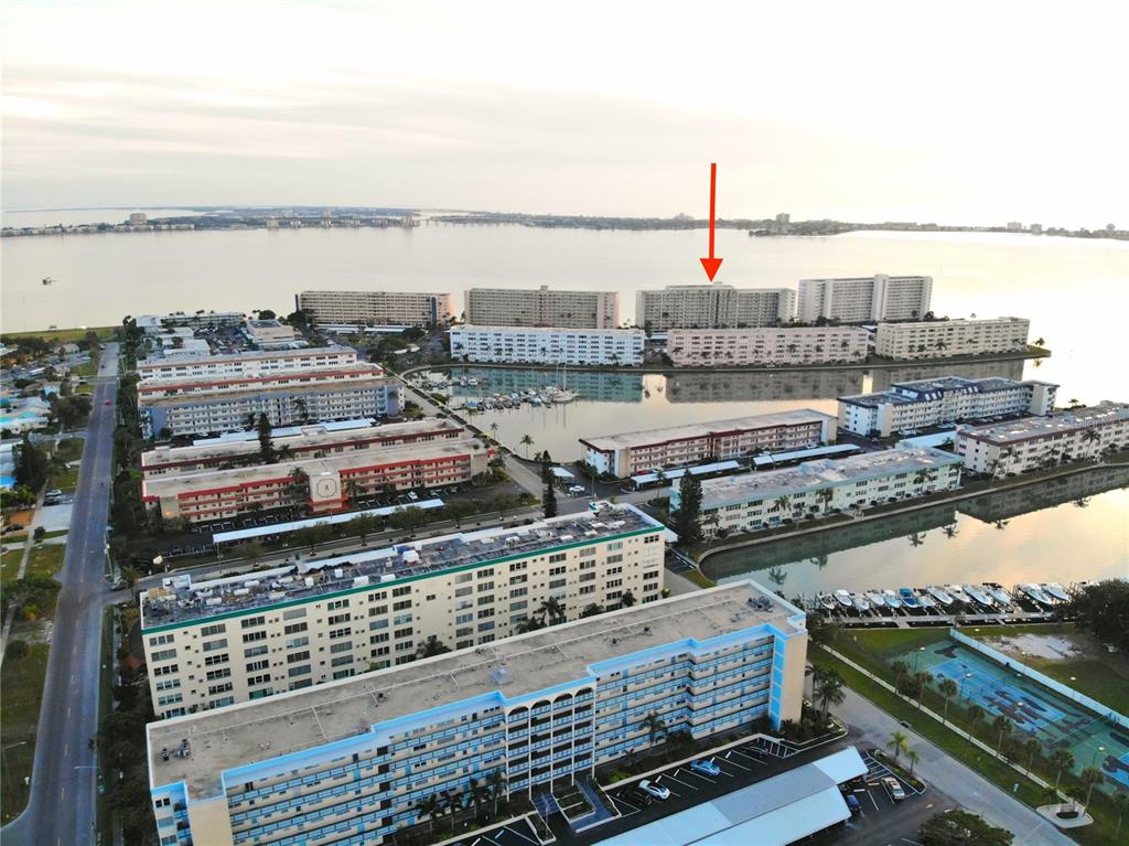 An aerial view shows multiple large apartment buildings surrounding a marina and a large bay — 6020 SHORE BOULEVARD S UNIT 701, GULFPORT, FL