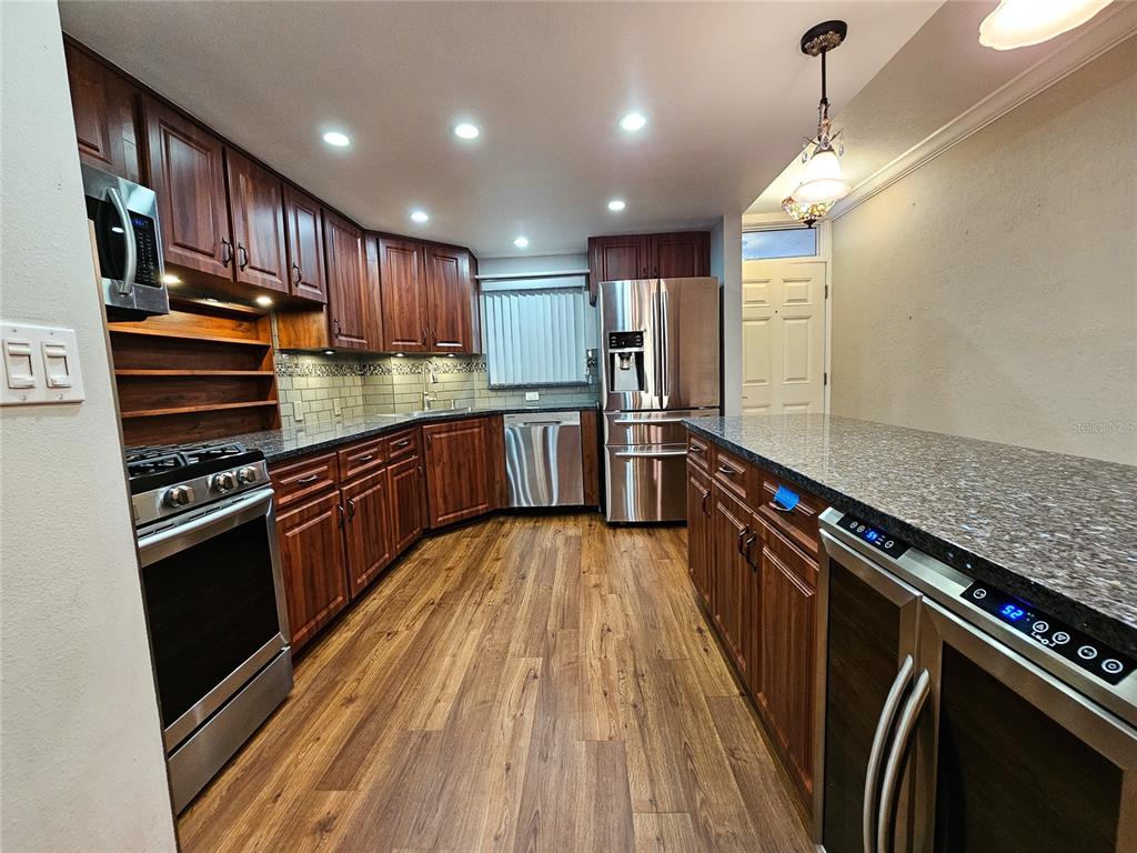 A kitchen features dark wood cabinets, stainless steel appliances, and granite countertops — 6020 SHORE BOULEVARD S UNIT 701, GULFPORT, FL
