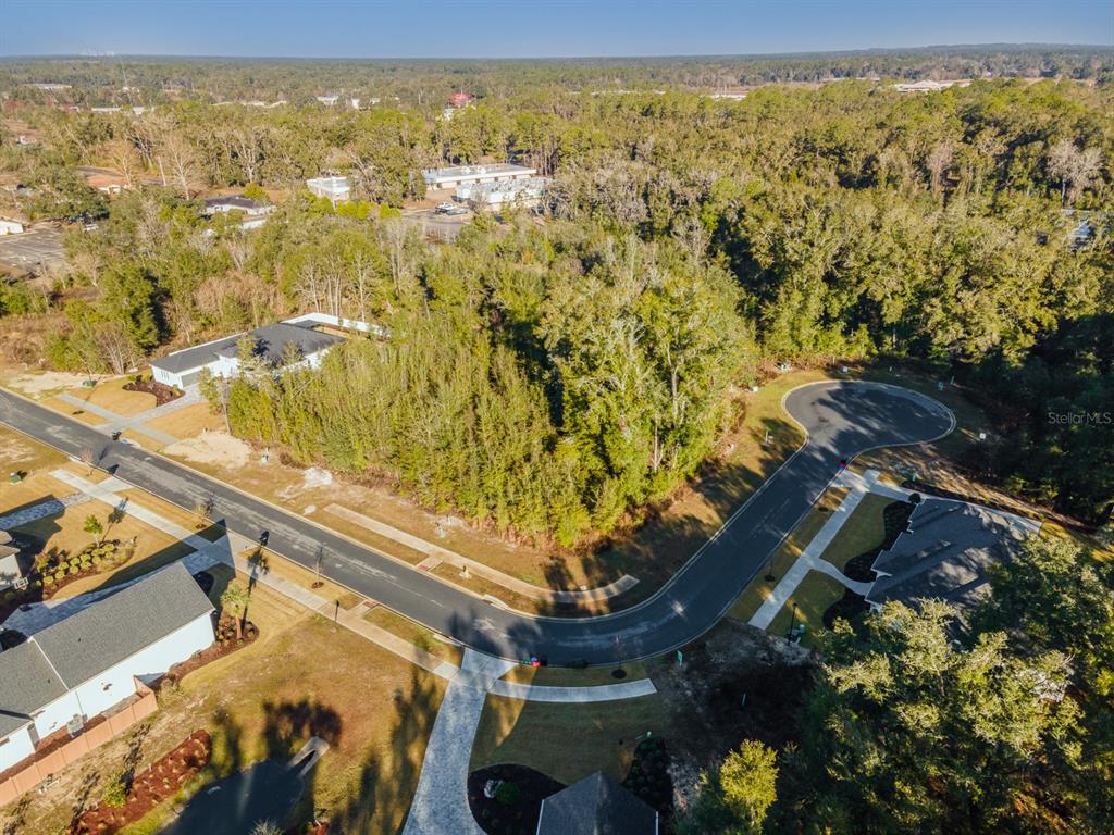 An aerial view shows a vacant, wooded residential lot situated on a curved suburban street — 620 SW 139TH COURT, NEWBERRY, FL