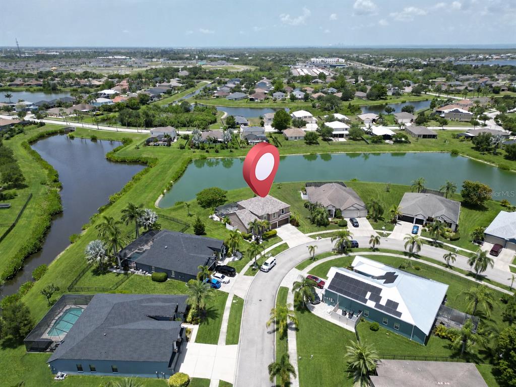 An aerial view shows a suburban neighborhood with houses surrounding a central pond — 360 HOPE BAY LOOP, APOLLO BEACH, FL