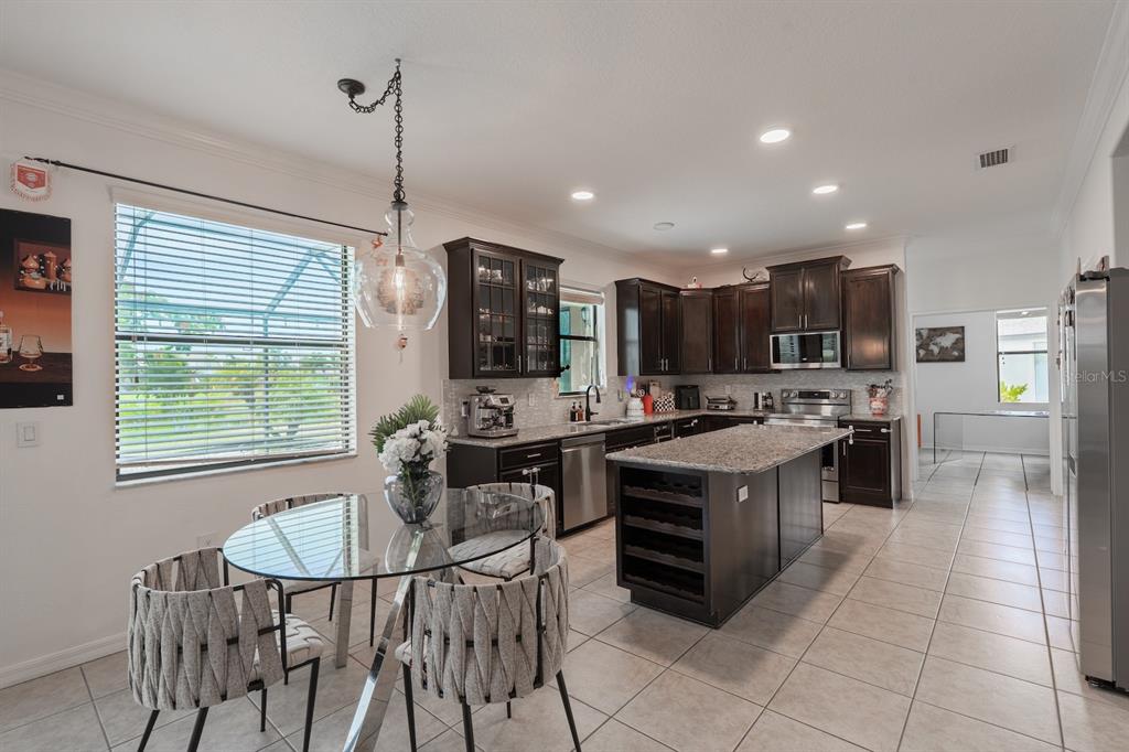 A kitchen with dark wood cabinets, granite countertops, a center island, and a dining area — 360 HOPE BAY LOOP, APOLLO BEACH, FL