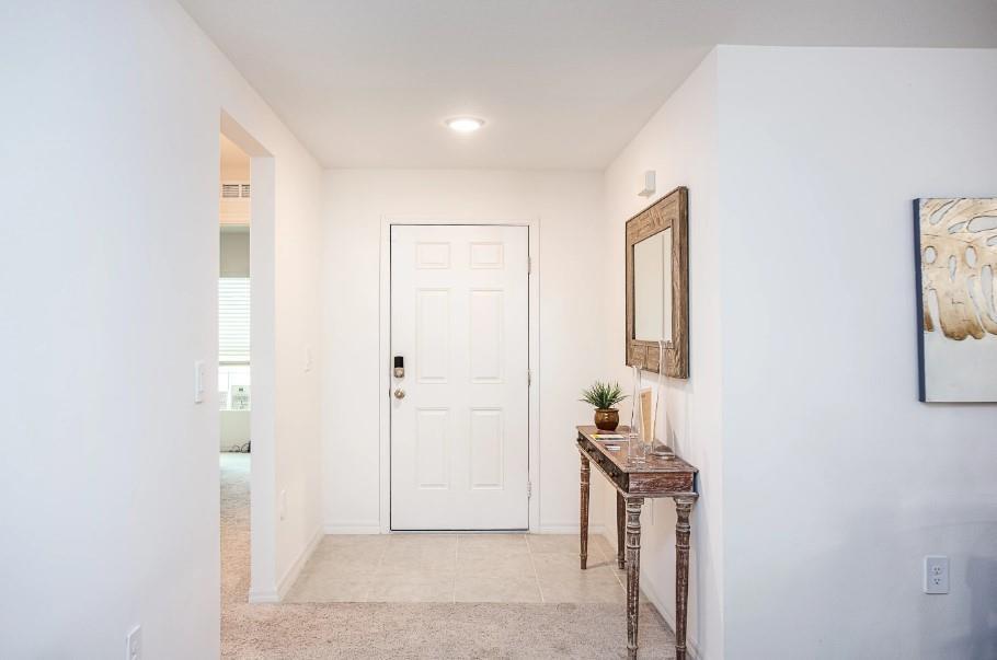 An entryway features a white door, a tiled floor, and a wooden console table — 1394 Schumann Drive, Sebastian FL 32958, SEBASTIAN, FL