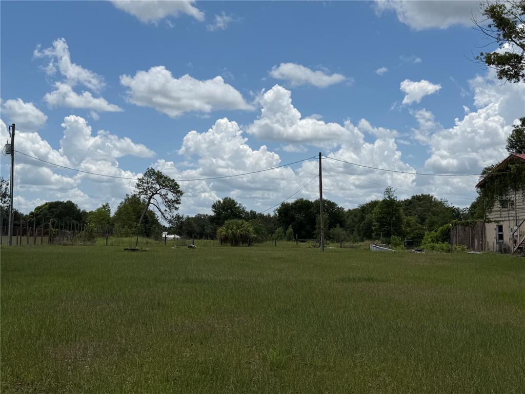 A grassy, open lot features utility poles and a partial view of a neighboring building — 4215 STEARNS ROAD, VALRICO, FL