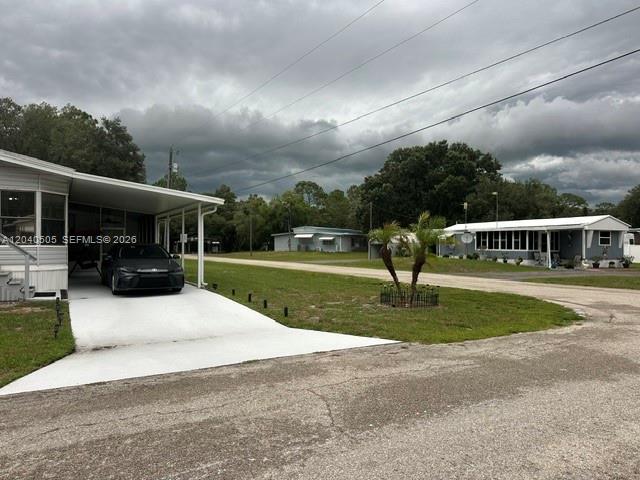 A view of two manufactured homes with carports and driveways under a cloudy sky — 8002 POGA LN, Sebring FL 33476, SEBRING, FL