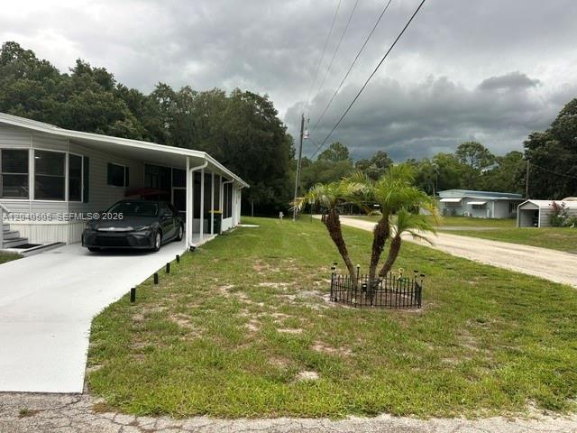 A mobile home with a carport and a small palm tree in the front yard — 8002 POGA LN, Sebring FL 33476, SEBRING, FL