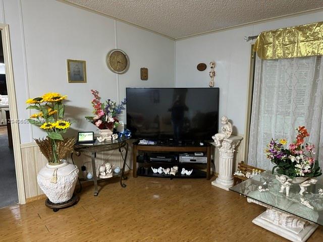 A living room features a large television on a stand, floral arrangements, and wood-look flooring — 8002 POGA LN, Sebring FL 33476, SEBRING, FL