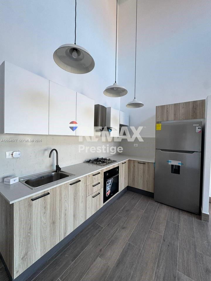 A modern kitchen features light wood cabinets, white upper cabinets, stainless steel appliances, and pendants — 1 La altagracia # 1, FL