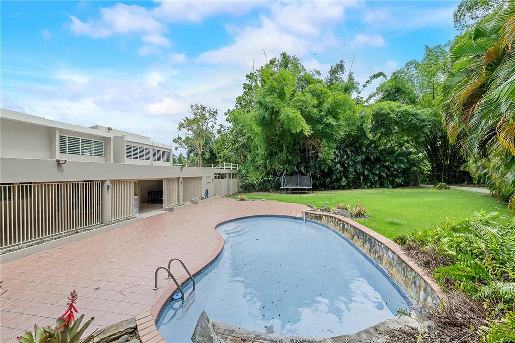 An outdoor backyard features a kidney-shaped swimming pool, a tiled patio, and a grassy lawn — Street #1 STREET #1 TINTILLO HILLS URB. UNIT 606, GUAYNABO, PR