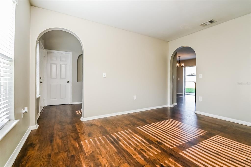 An interior view showing a room with wood-look flooring, two arched doorways, and white walls — 10405 FLY FISHING STREET, RIVERVIEW, FL
