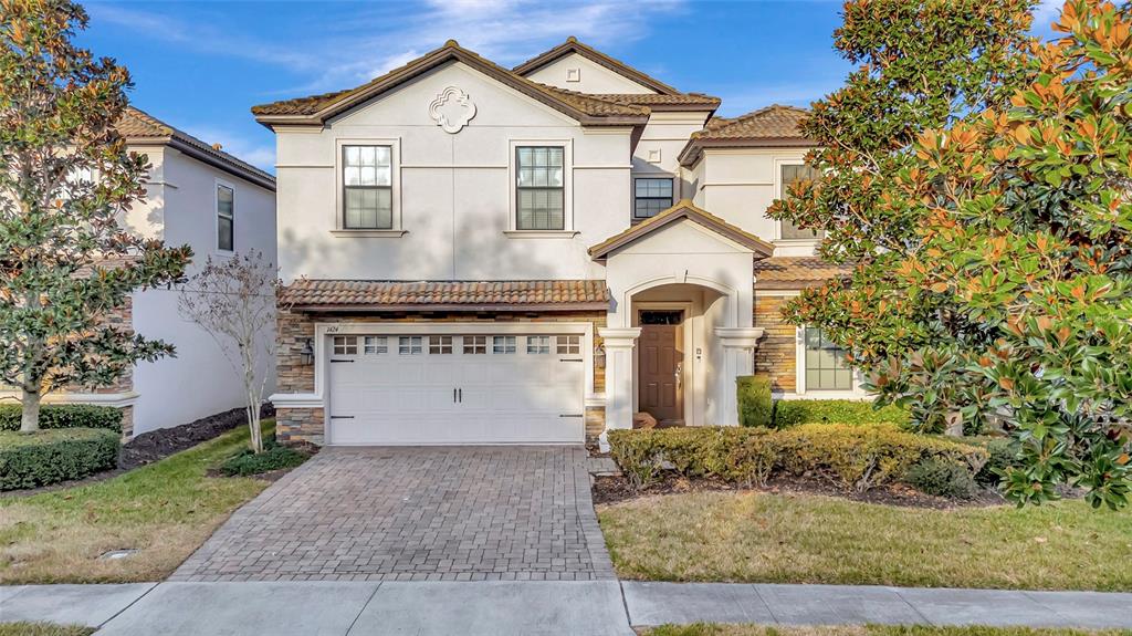 A two-story house with a white stucco facade, stone accents, and a paved driveway — 1424 WEXFORD WAY, DAVENPORT, FL