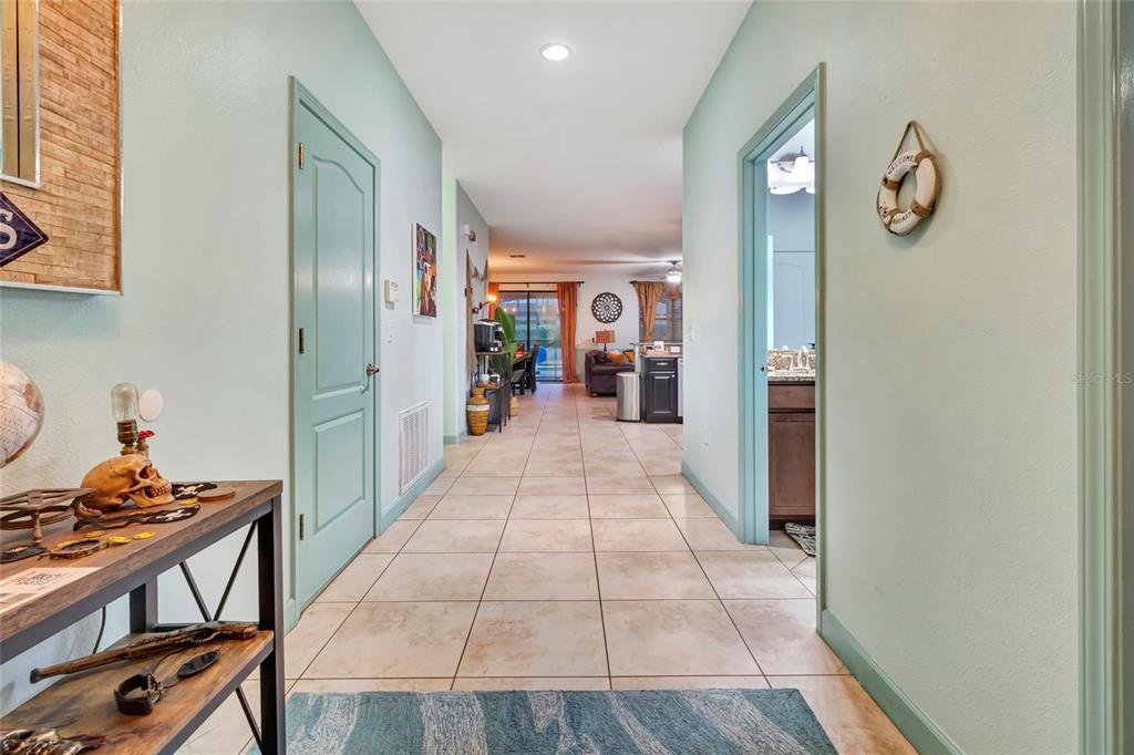 A tiled hallway leads from a foreground entryway toward an open-concept living and kitchen area — 1424 WEXFORD WAY, DAVENPORT, FL
