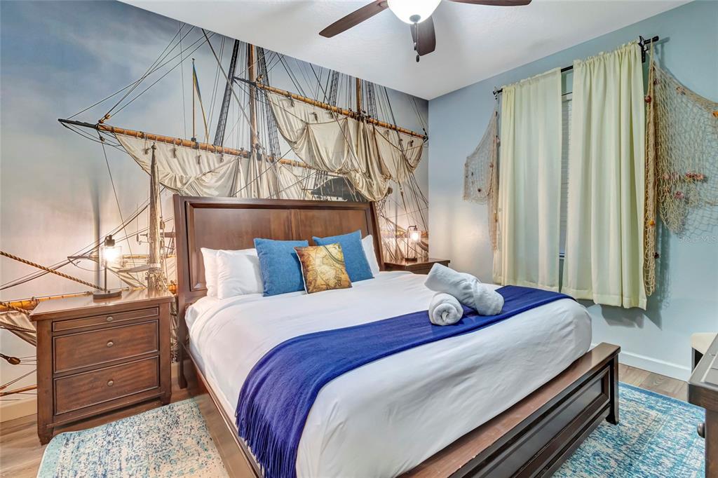 A bedroom features a nautical-themed mural, a wooden bed frame, and light-colored curtains — 1424 WEXFORD WAY, DAVENPORT, FL