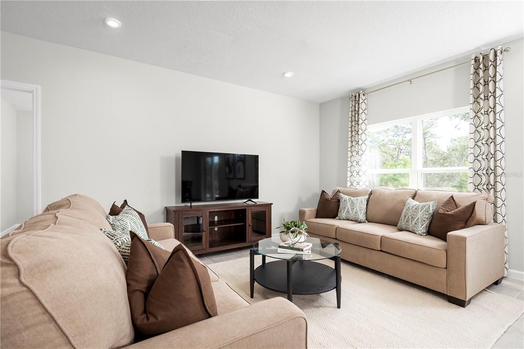 A living room features two beige sofas, a glass-topped coffee table, and a television console — 6951 SUNDIAL DRIVE, LAKELAND, FL