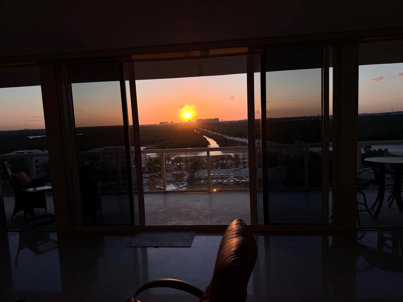 A view of a sunset over a landscape from a room with large sliding doors — 6051 N Ocean Drive # 1003, Hollywood FL 33019, HOLLYWOOD, FL