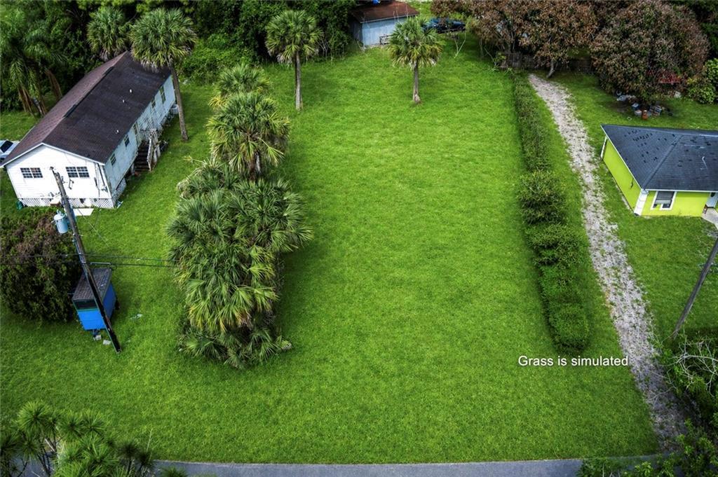 An aerial view shows a vacant, grassy residential lot situated between two existing houses — VERO BEACH, FL