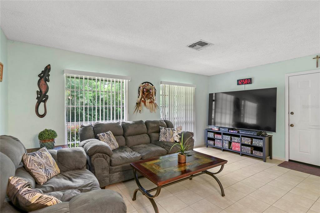 A living room features a grey sofa, a coffee table, and a large television — 1507 GROVE STREET, MAITLAND, FL