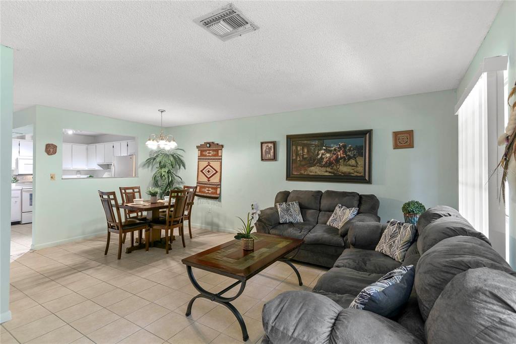 A living room and dining area with tile flooring, gray sofas, and light green walls — 1507 GROVE STREET, MAITLAND, FL