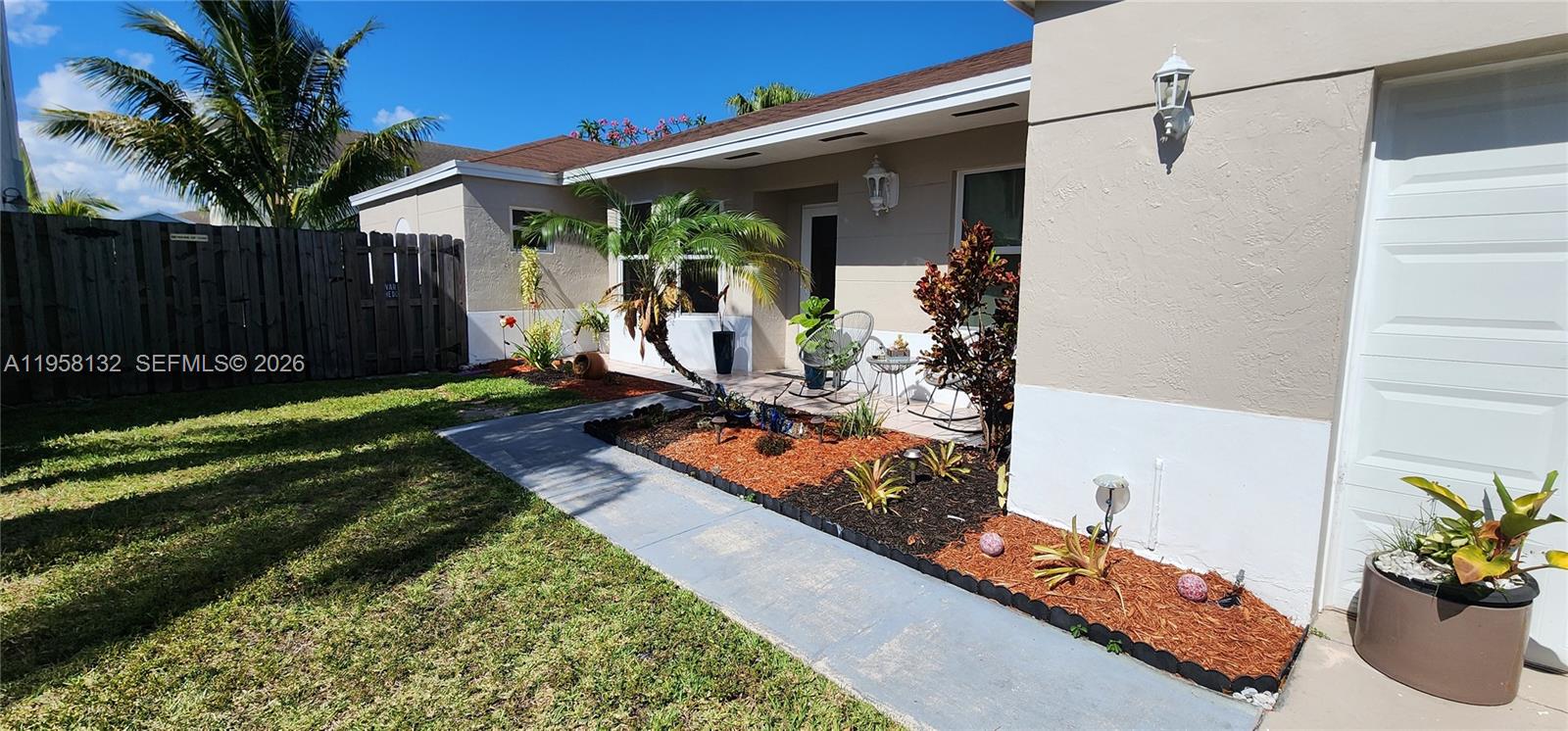 A single-story house exterior features a front walkway, landscaped garden beds, and a wooden fence — 9829 SW 221st St, Cutler Bay FL 33190, CUTLER BAY, FL