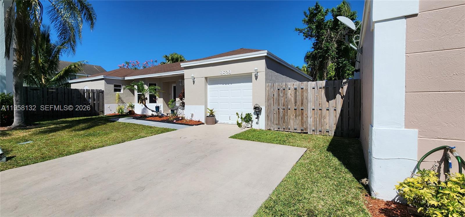 A single-story house with a white garage door, concrete driveway, and wooden fence — 9829 SW 221st St, Cutler Bay FL 33190, CUTLER BAY, FL