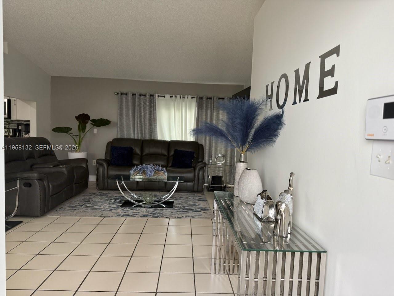 A living room features tiled floors, dark leather sofas, and a glass console table — 9829 SW 221st St, Cutler Bay FL 33190, CUTLER BAY, FL