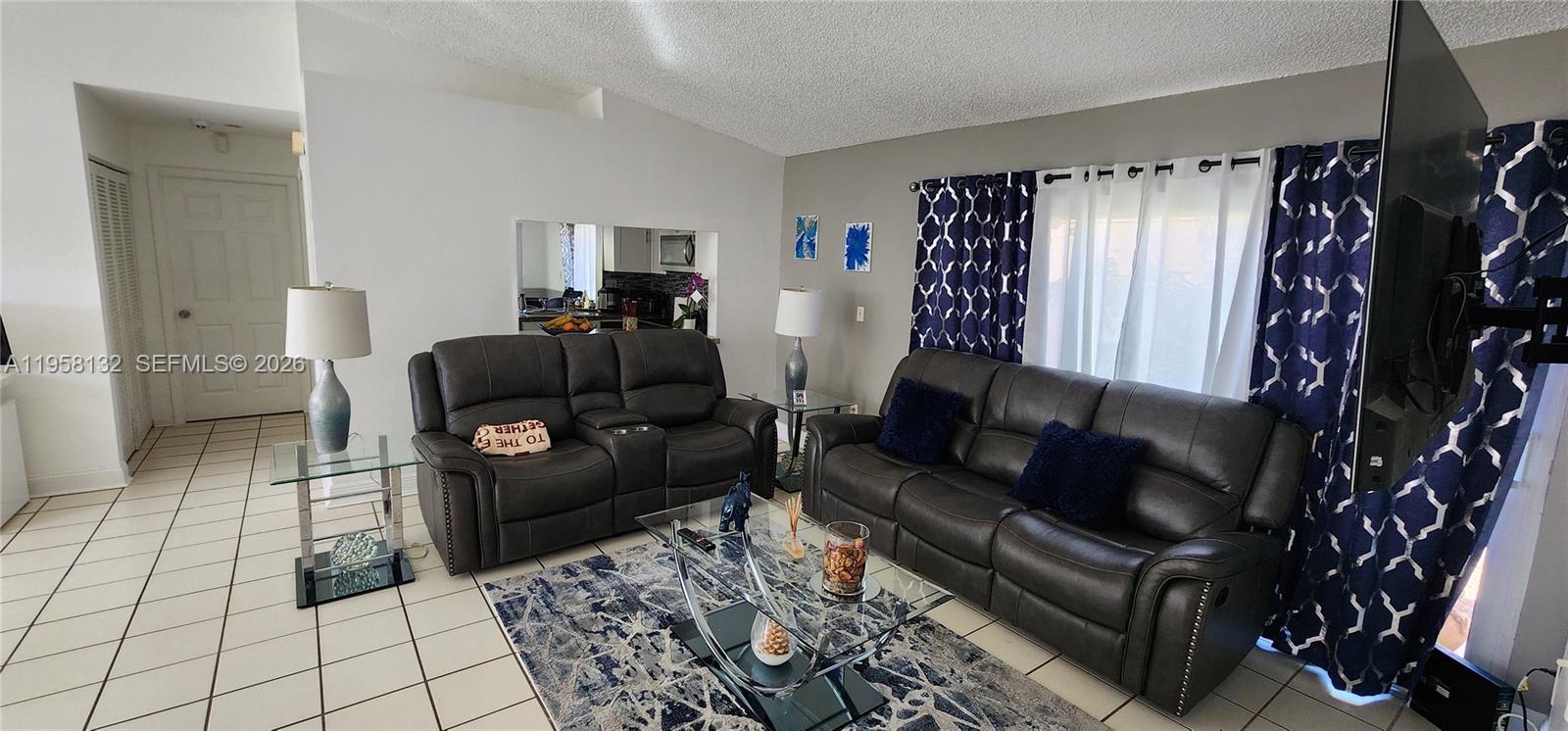A living room features two dark leather sofas, a glass coffee table, and tiled floors — 9829 SW 221st St, Cutler Bay FL 33190, CUTLER BAY, FL
