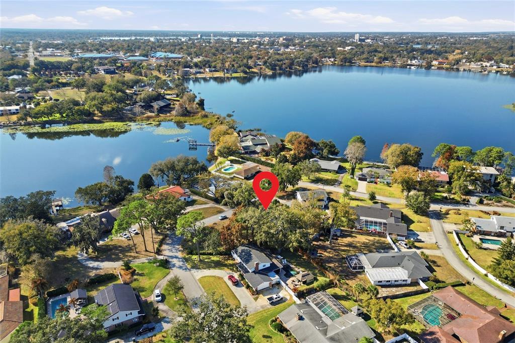 An aerial view shows a lake at sunset with residential homes and docks along the shore — 148 LAKE OTIS ROAD, WINTER HAVEN, FL