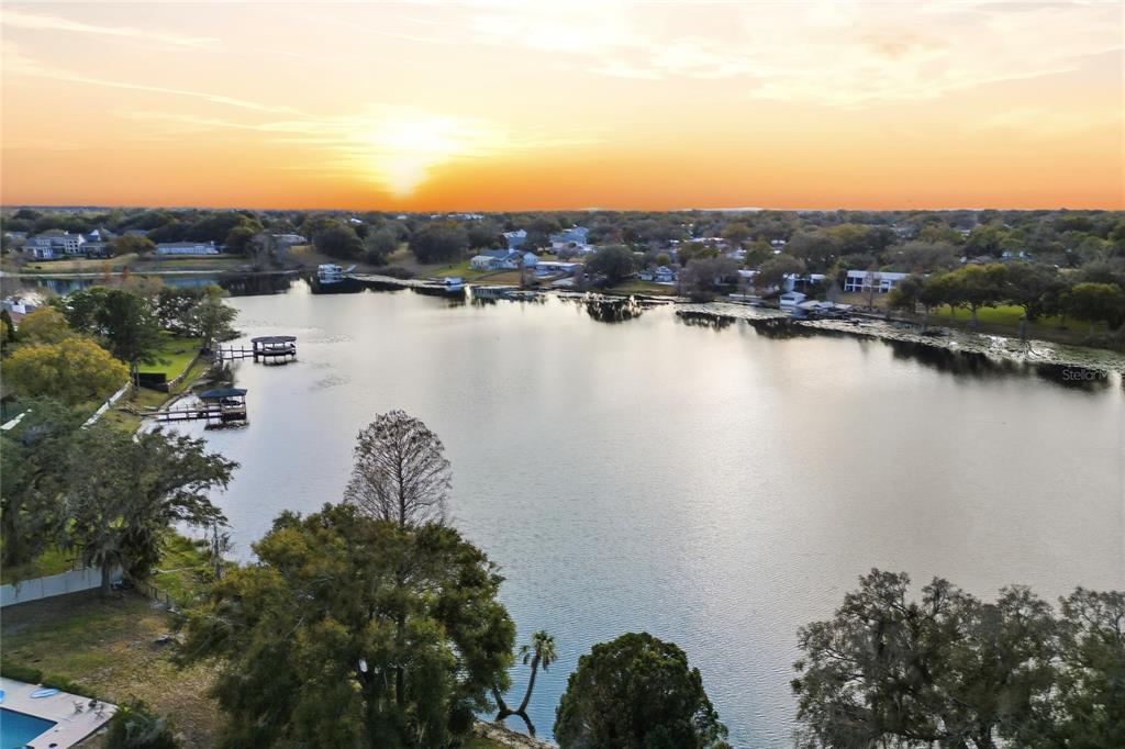 An aerial view shows a residential neighborhood with houses, trees, and a large lake — 148 LAKE OTIS ROAD, WINTER HAVEN, FL