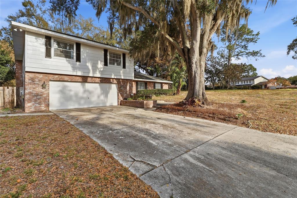 A two-story house with a brick and white siding exterior features a large concrete driveway — 148 LAKE OTIS ROAD, WINTER HAVEN, FL